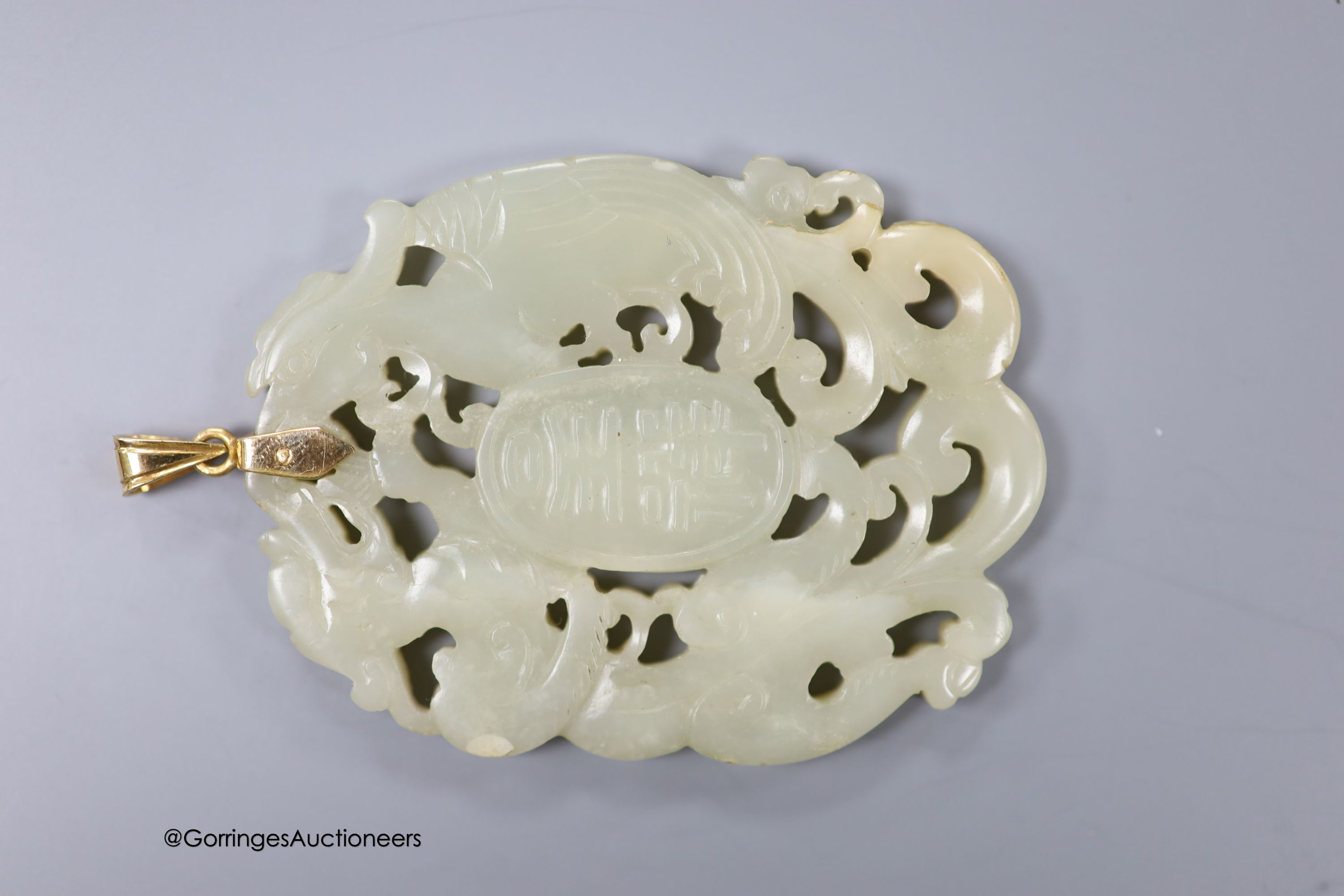 A Chinese yellow metal amounted jade pendant, 63mm, carved with dragons and character marks.